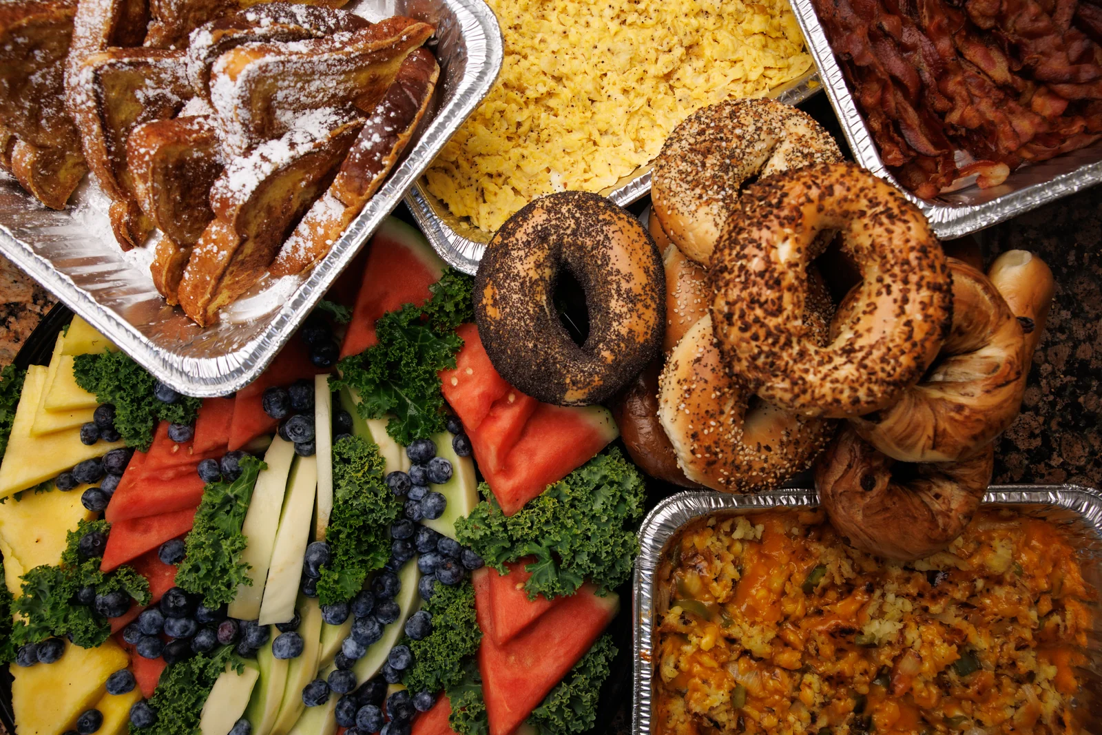 Bagel Boyz breakfast catering spread with bagels, eggs, bacon, French toast, fruit and potatoes.
