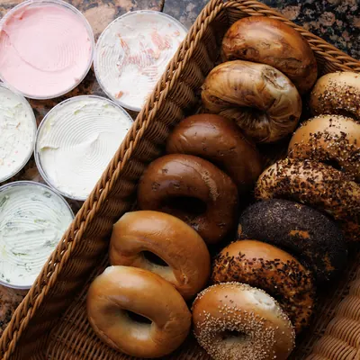 A basket of fresh bagels with tubs of cream cheese